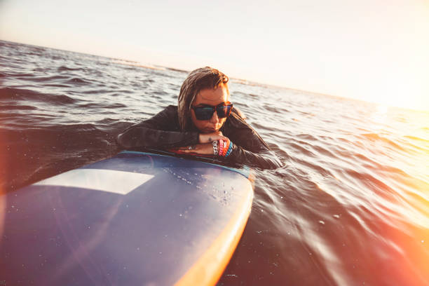 istock Girl surfer resting on surfboard 694237676