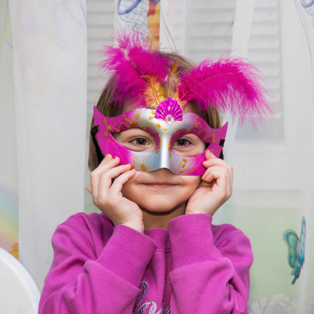istock Young female child with red Mardi Gras mask 694237984