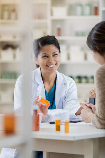 cheerful female pharmacist talks with customer - prescription doctor rx pharmacist imagens e fotografias de stock