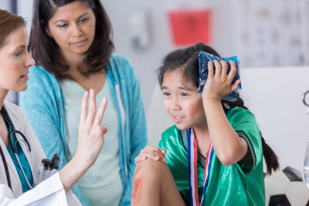 ER doctor examines dazed injured soccer player Serious female ER doctor holds up three fingers while talking with injured female elementary age soccer player. The doctor is asking the girl how many fingers she is holding up. The girl is wearing a medal and soccer uniform. head stock pictures, royalty-free photos & images