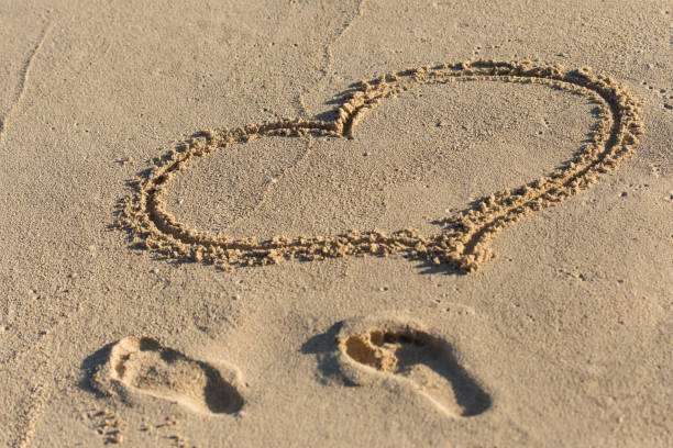 istock Shape of heart and footprints on sand 694243796