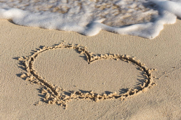 istock Shape of heart on sandy beach with wave's foam 694243870