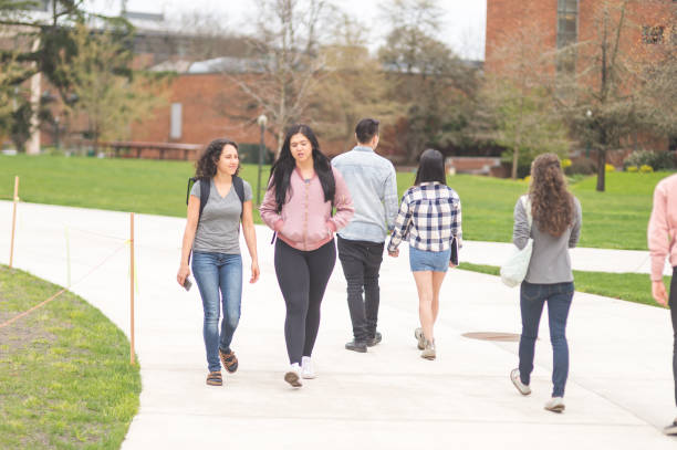 istock Multiethnic group of college students hang out in between classes on sidewalk, talking and smiling 694249968