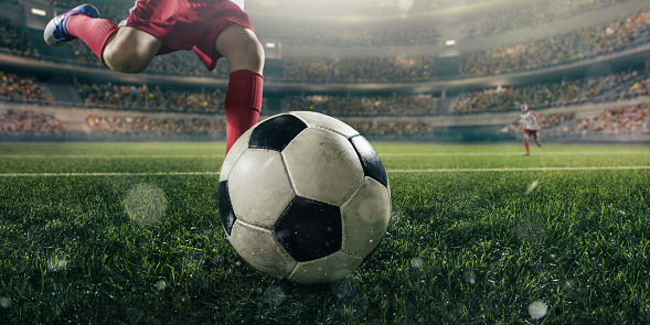 Close up soccer kids player with ball. Soccer kids players in action in 3D dramatic stadium. Behind the players is a stadium with fans in the stands.