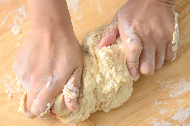 istock kneading bread dough on wooden board 694274034