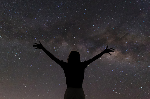 Woman lift two hands happy succeeding with beautiful milky way.