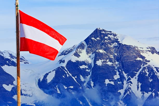 patriotismus: österreichische flagge und pole wicklung über majestätische hohe tauern schneebedeckten österreichischen bergkette bei sonnenaufgang - grossglockner-massiv, tiroler alpen - alpenglow tirol sunrise snow stock-fotos und bilder