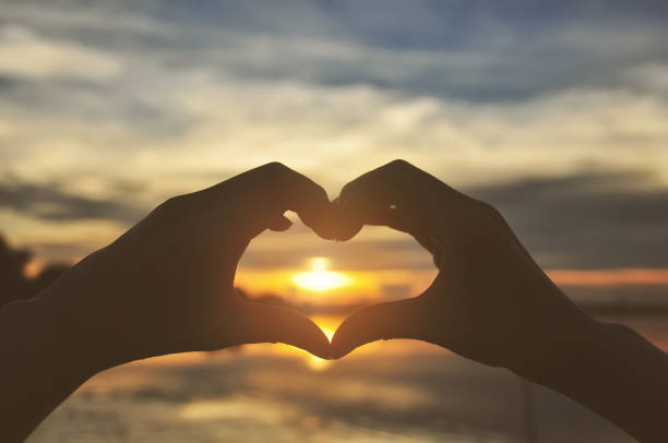 istock Silhouette hands forming heart shape with sunset 694307082