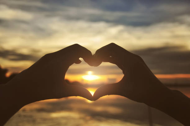istock Silhouette hands forming heart shape with sunset 694307602