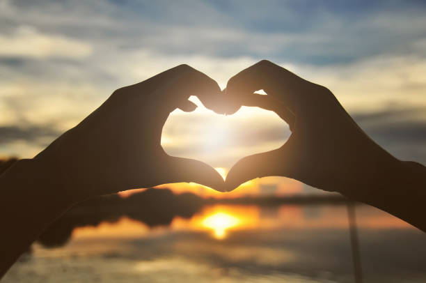istock Silhouette hands forming heart shape with sunset 694307644