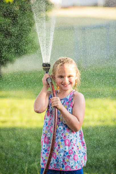 istock Girl Playing With Water Hose In Back Yard 694311204