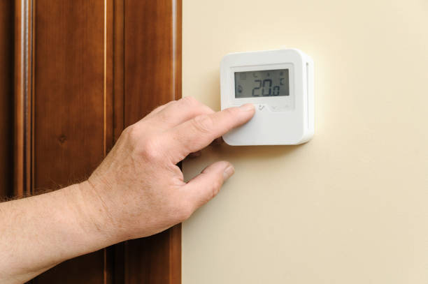 istock Man is changing  settings of a thermostat. 694319580