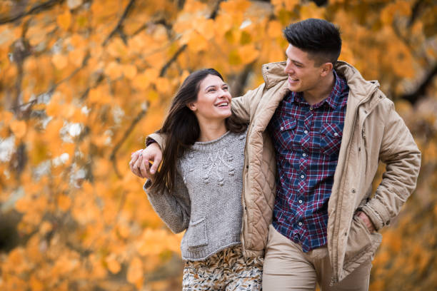 istock Cheerful couple walking embraced in autumn day and communicating. 694325590