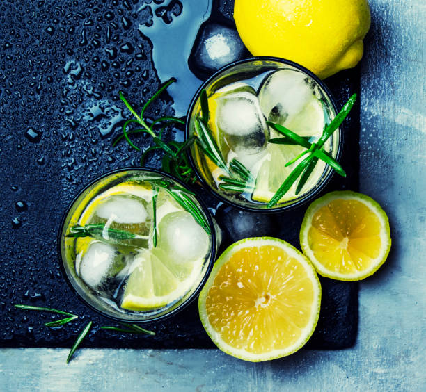 Summer cocktail with lemon, rosemary and ice Summer cocktail with lemon, rosemary and ice, gray background, top view green tea cocktail bar stock pictures, royalty-free photos & images