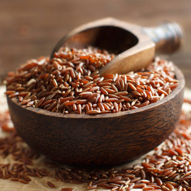 istock Uncooked Red rice in a bowl with a wooden spoon 694332424