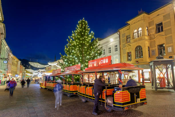 Villach at Christmas, the Hauptplatz - Austria Sightseeing tourist train passing in the Hauptplatz - Main Square - of Villach, in the federal state of Carinthia, among tourists and locals. Every year the city celebrates the advent with a traditional Christmas market. villach stock pictures, royalty-free photos & images