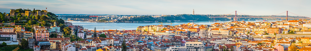 Warm sunlight of daybreak illuminating the colourful villas and crowded rooftops of central Lisbon, Portugal’s vibrant capital city.