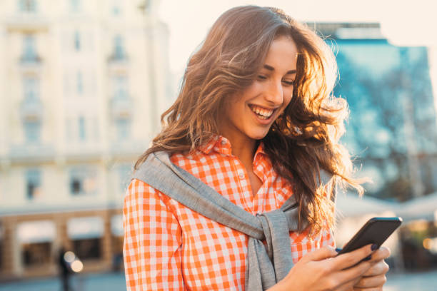 istock Beautiful woman texting outdoors 694364894