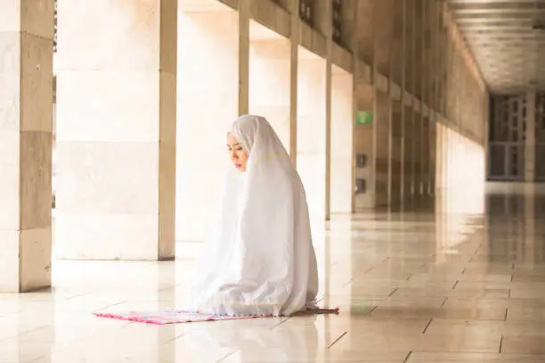 Muslim woman wearing prayer veil, praying in the mosque