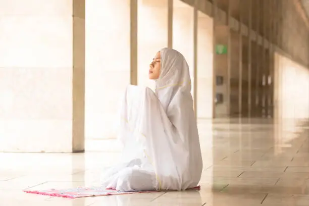 Muslim woman wearing prayer veil, praying for Allah, muslim god