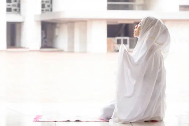 Woman praying in mosque while wearing prayer veil