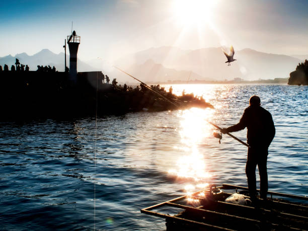 silhouetted man fishing on dock during sunset in Old-Town, Antalya, Turkey