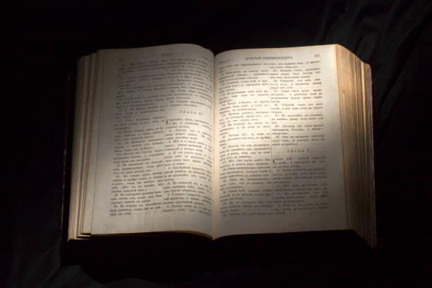 Open book with light spotlight on text. Reading of opened book educate reader. Ancient Bible text reading on black background. Russian bible stock photo