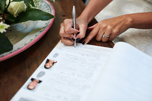 Cropped shot of an unrecognisable bride signing paperwork on her wedding day