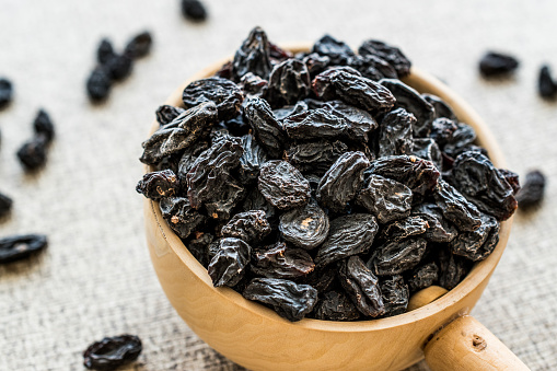 Organic Dried Raisins or Grape in wooden ladle. Organic Food Concept.