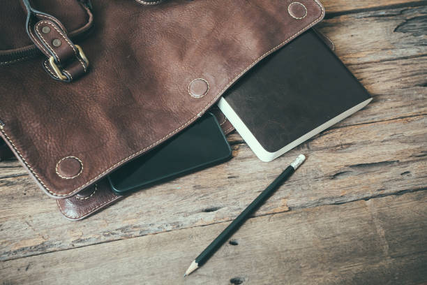 notebook and smartphone with leather bag on wooden table