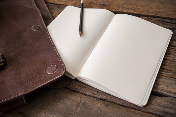 istock blank notebook with leather bag on wooden table 694393448