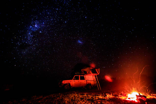 Camping with campfire and stars. Camping at night with fire and stars in the Hwange National Park, Zimbabwe. long shutter speed stock pictures, royalty-free photos & images