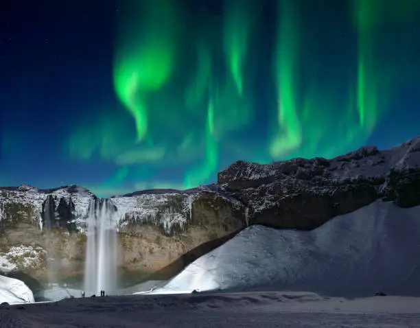 The Skogafoss waterfall and green aurora in midnight sky, Iceland.