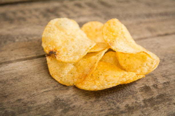 istock Crispy potato chips on wooden background 694422626