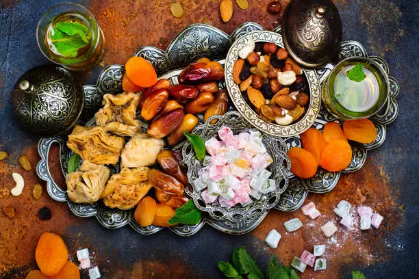 Ramadan Kareem holiday table with dry fruits, nuts, dates, baklava. Eastern abundance. Copy space