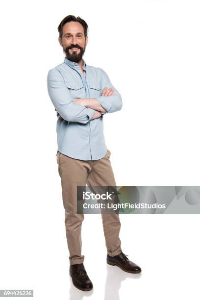 Adult Smiling Man In Casual Clothes Standing With Crossed Arms And Looking At Camera Isolated On White Stock Photo - Download Image Now