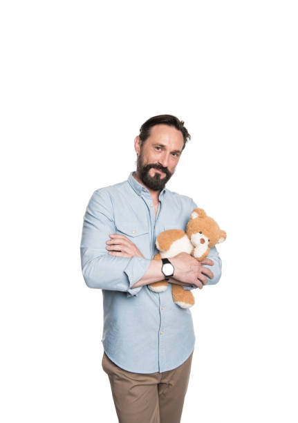 istock Smiling bearded mature man holding teddy bear and smiling at camera 694429848