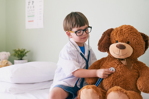 Shot of a little boy pretending to be a doctor while examining his teddybear