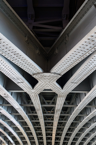 Detail of riveted steel beams supporting span of bridge crossing the River Thames
