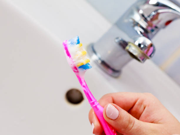 istock Hand holding toothbrush in bathroom 694434238