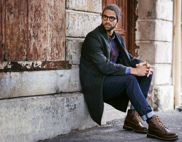 Take a moment to enjoy the streets of the city Shot of a handsome young man taking a seat on the sidewalk in the city street style stock pictures, royalty-free photos & images