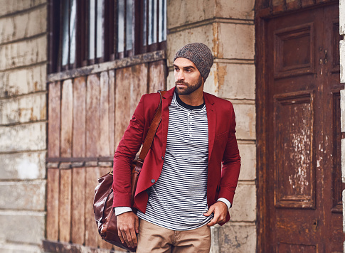 Shot of a handsome young man with a red jacket taking a walk in the streets while carrying his bag