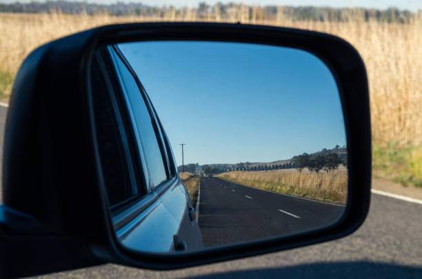View of a road in the rear view mirror View of a country road in Victoria, Australia seen in a car rear view mirror reflection standing water country road local landmark stock pictures, royalty-free photos & images