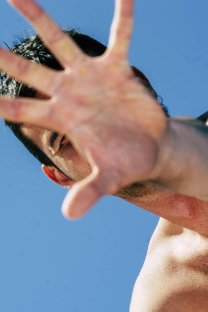 istock boy at the beach covers his face with his hand, STOP 694454472