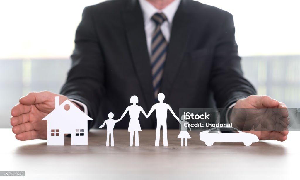 Concept of home, family and car insurance Insurer protecting house, family and car with his hands Insurance Agent Stock Photo