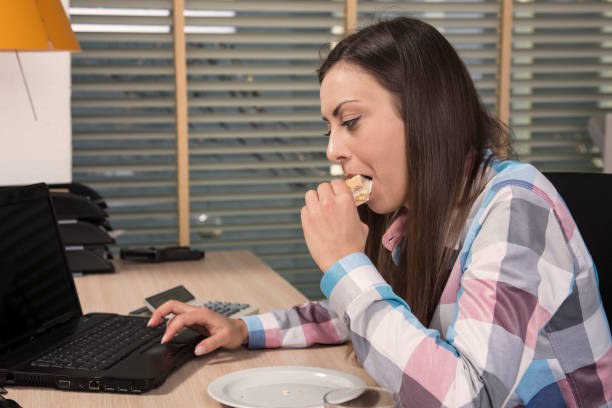 istock The secretary eats the sandwich and works on the computer 694457258