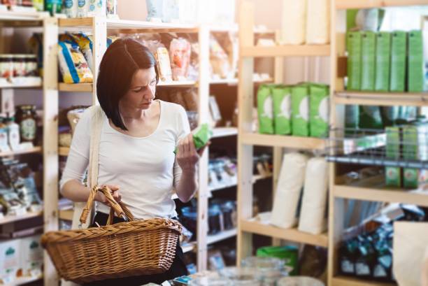 Woman reading product information on label Woman choosing products in ecological shop with healthy food and reading product information on label labeling photos stock pictures, royalty-free photos & images