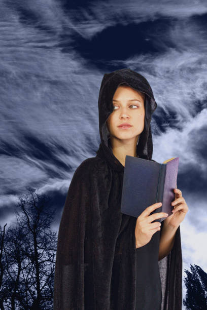 istock Book reading widow witch in black hood moonlit background 694474848