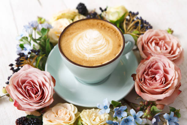 istock Cappuccino coffee and flowers composition on white wood 694482358