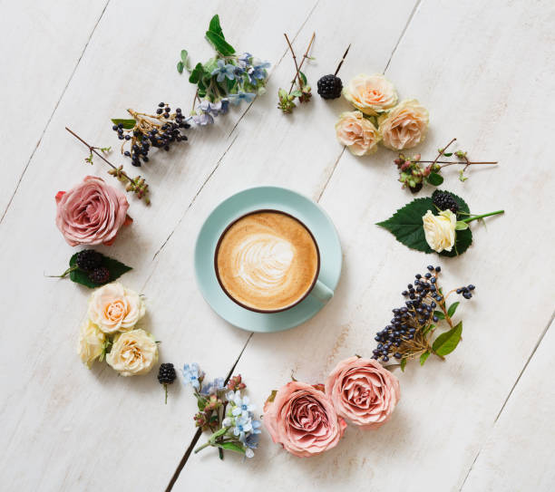 istock Cappuccino coffee and flowers composition on white wood 694484488